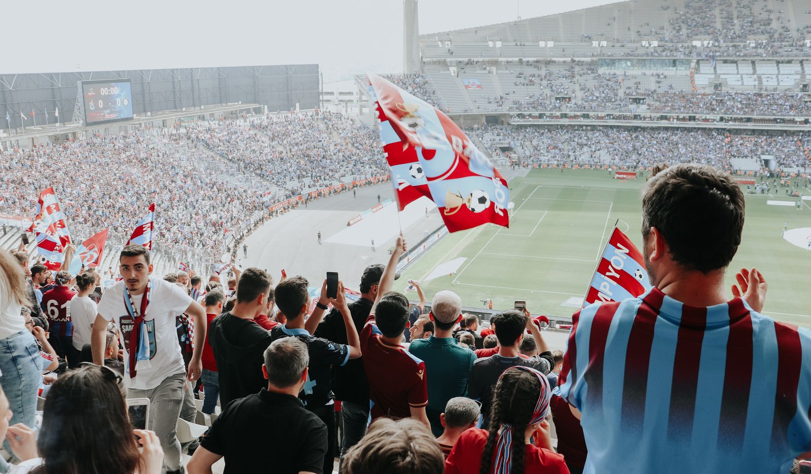 Fans waving flags inside a packed football stadium